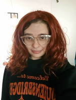 Photo of Irina looking directly at the camera. She has glasses on and dubious red hair. This is not how Irina actually looks. She is a wearing a wig and has fake glasses on.